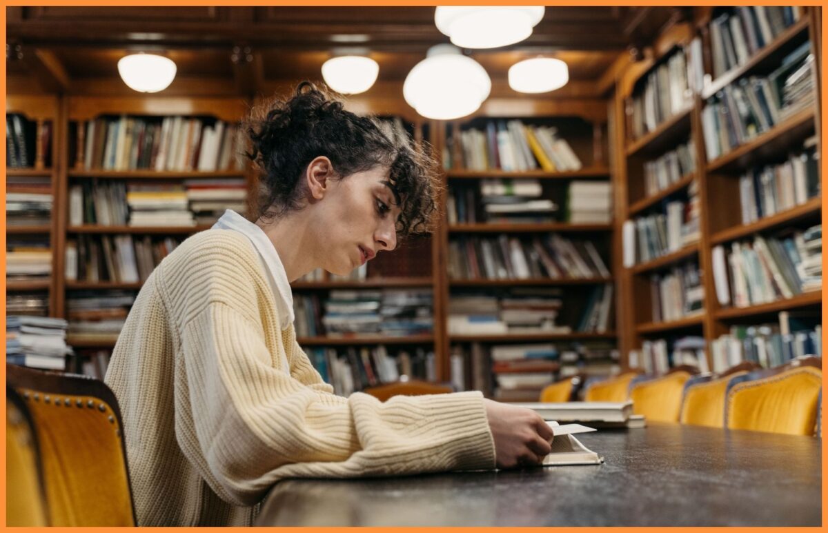 Studentka czytająca publikacje naukowe i książki w bibliotece.